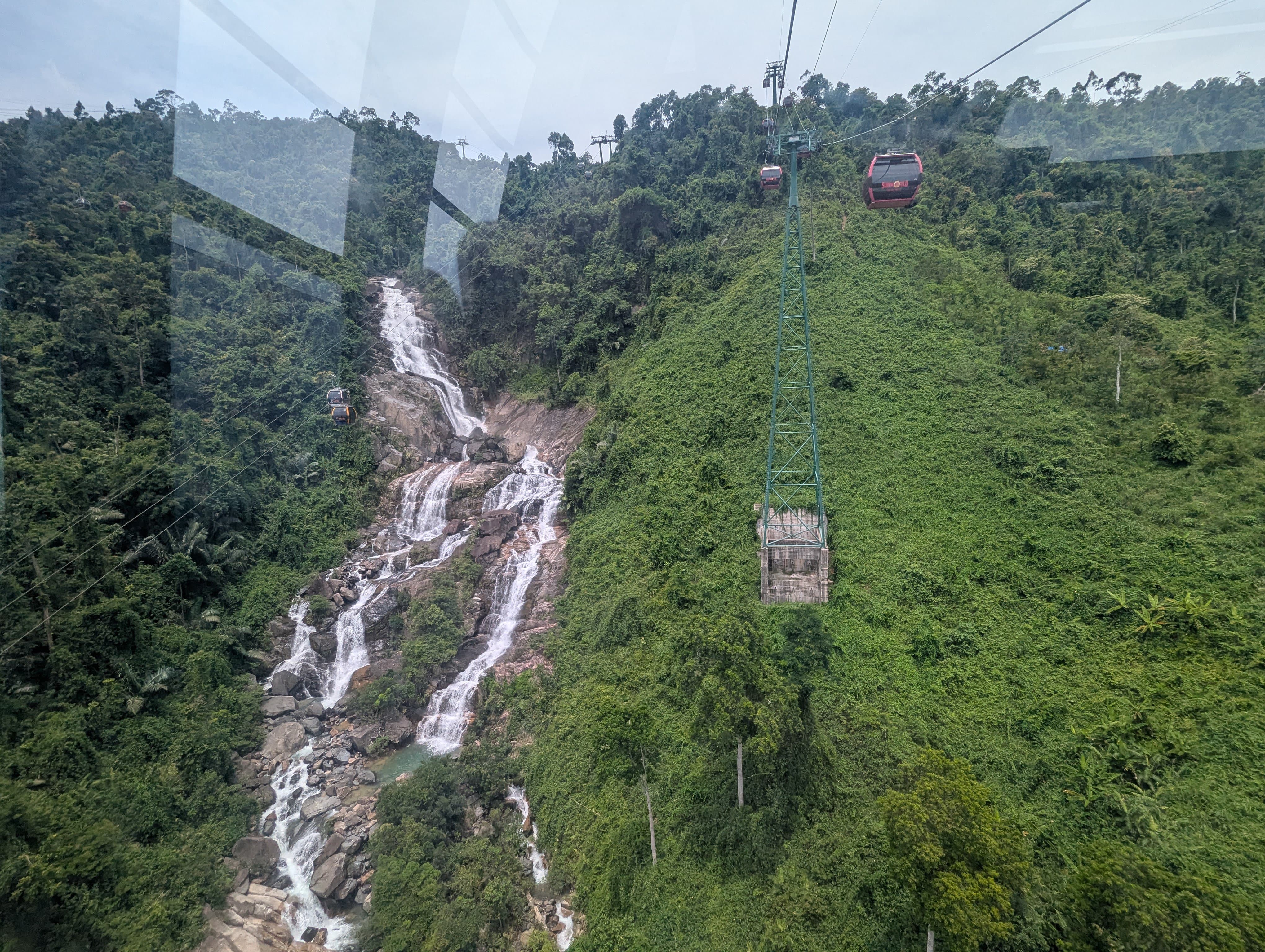 Téléphérique survolant la cascade Toc Tien entourée de végétation luxuriante à Ba Na Hills.