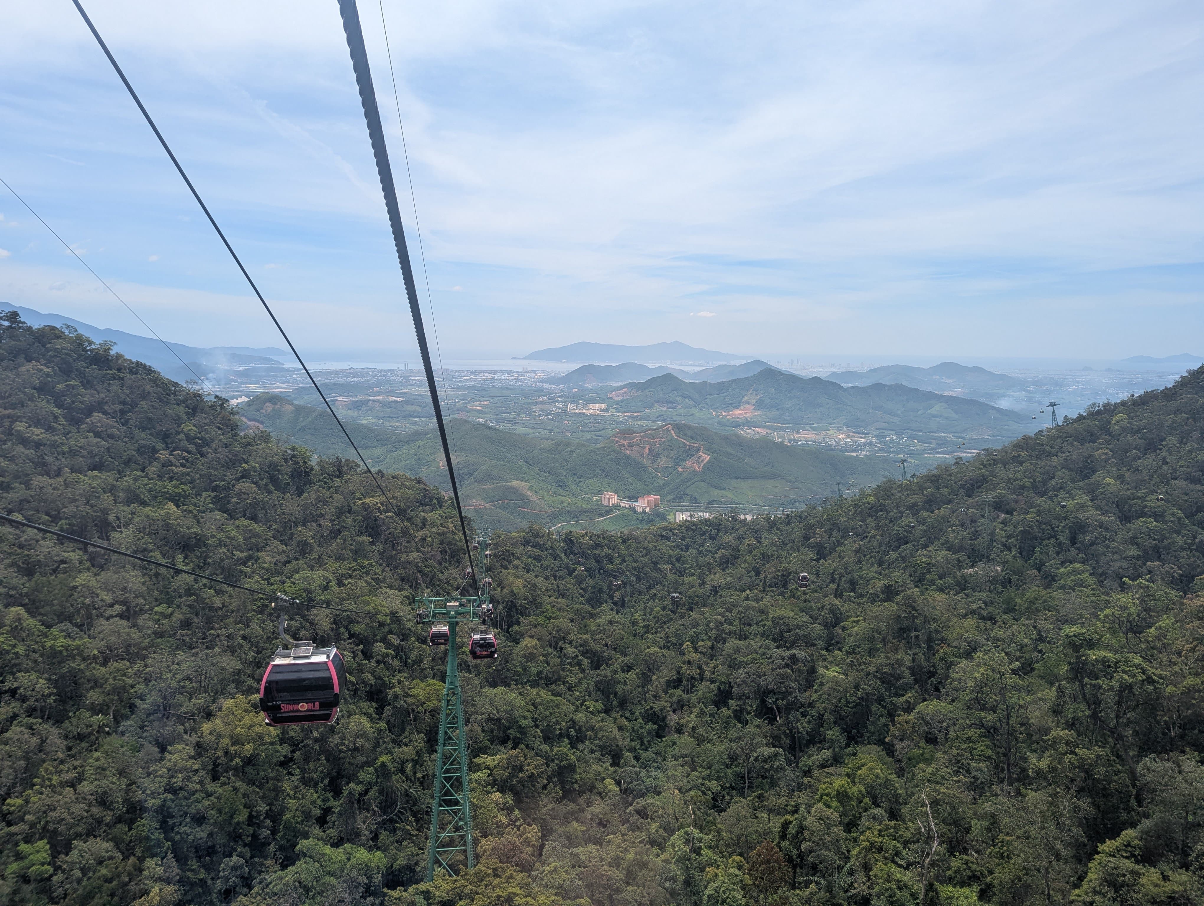 Vue spectaculaire sur la vallée depuis le téléphérique de Ba Na Hills, entouré de montagnes verdoyantes.