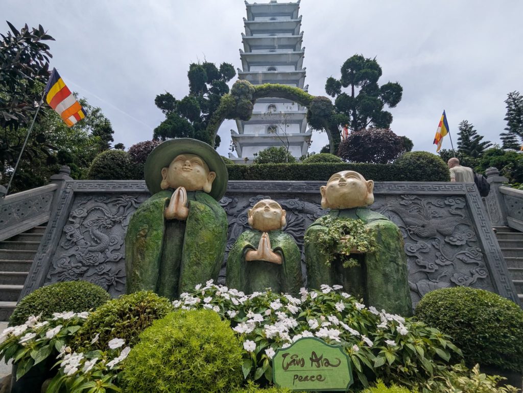 Trois statues de moines priants devant une pagode bouddhiste à Ba Na Hills.